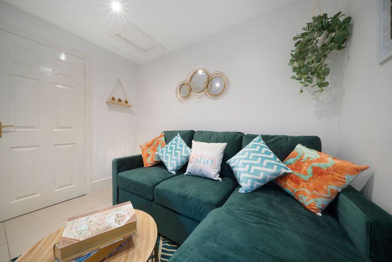 Living room with dark green corner sofa, colorful cushions, wooden coffee table and wall decor