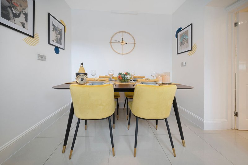 Modern dining room with black table, yellow upholstered chairs, and wall art
