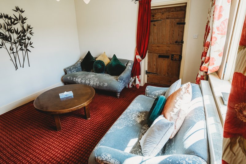 Living room with blue sofa, wooden coffee table, red carpet and matching curtains