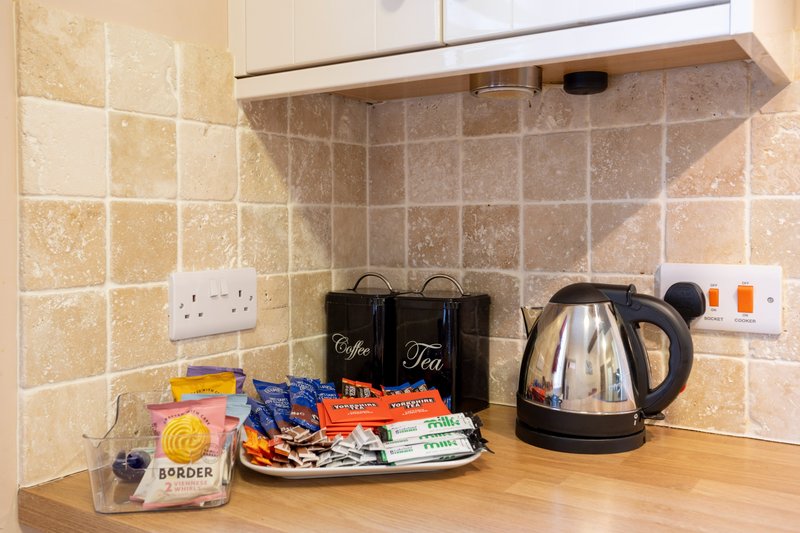 Kitchen countertop with kettle, coffee and tea canisters, and various packaged items