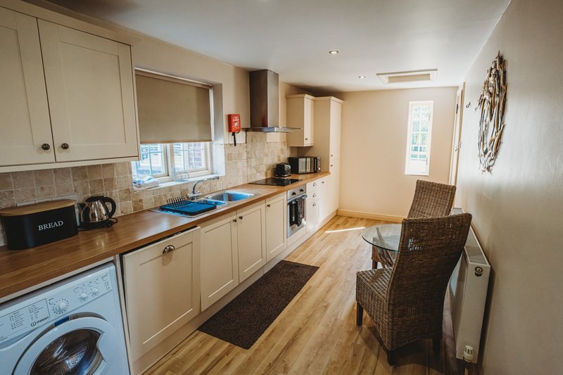 Kitchen with cream cabinets, wooden countertop, appliances and dining chairs