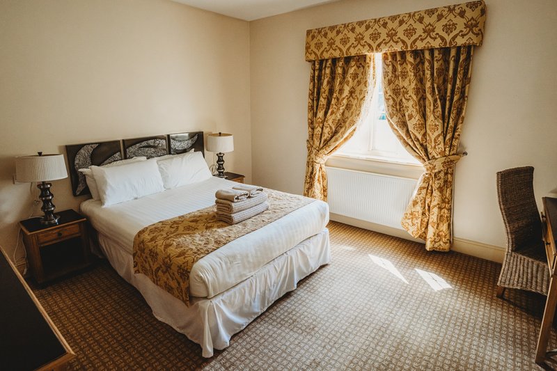 Traditional bedroom with double bed, gold patterned curtains and matching bedspread