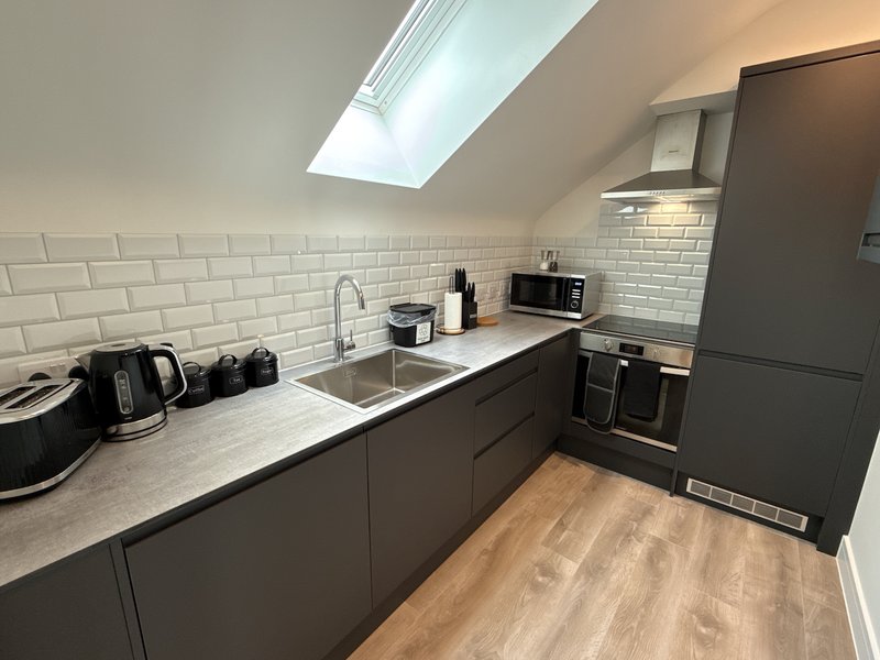 Modern kitchen with dark cabinetry, white subway tile splashback, skylight and stainless steel appliances
