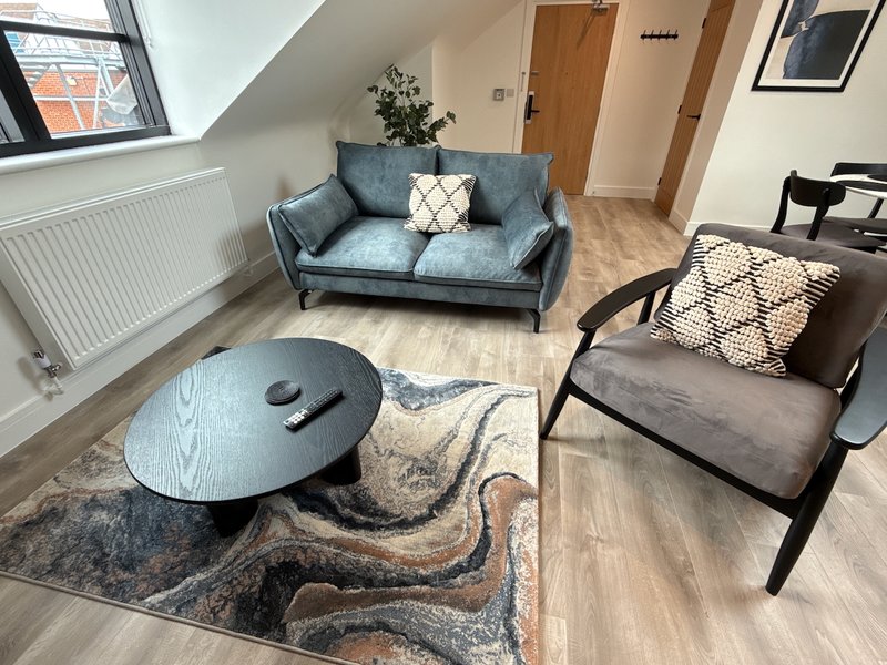 Modern living room with blue sofa, black armchair, round coffee table and patterned rug