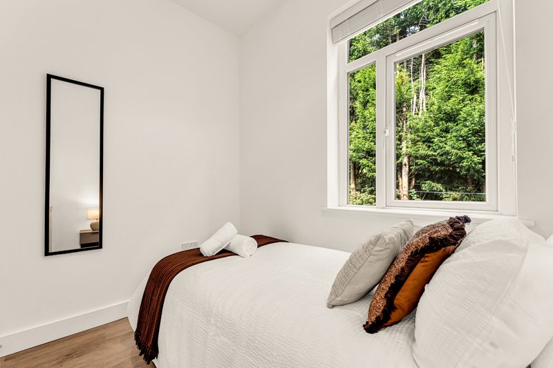 Bright bedroom with single bed, white bedding, decorative pillows and wall mirror