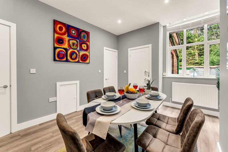 Modern dining room with set table, grey walls, framed abstract artwork and large window
