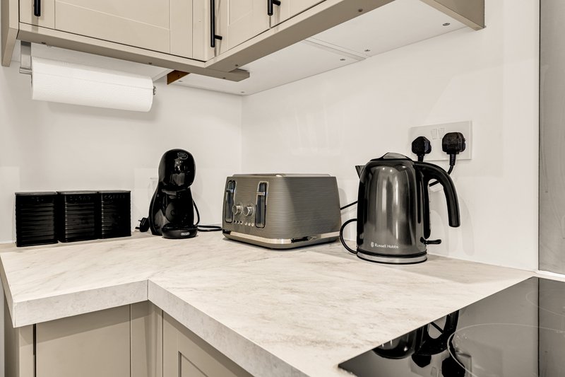 Modern kitchen counter with appliances including coffee maker, kettle, and black small appliances