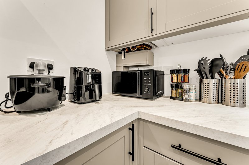 Modern kitchen countertop with appliances, utensil holders, and white cabinetry