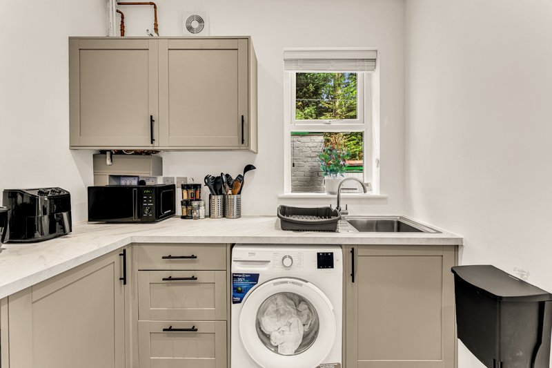 Modern kitchen with washing machine, sink, beige cabinetry and window view