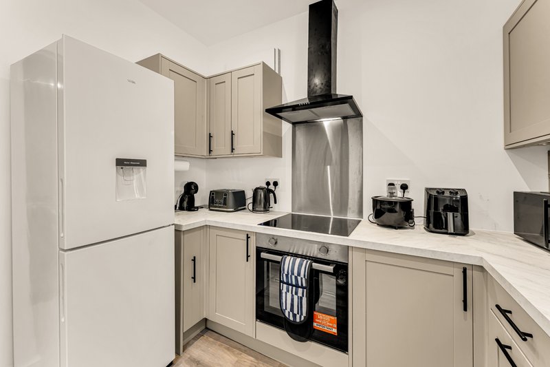Modern kitchen with cream cabinets, stainless steel appliances, and black range hood