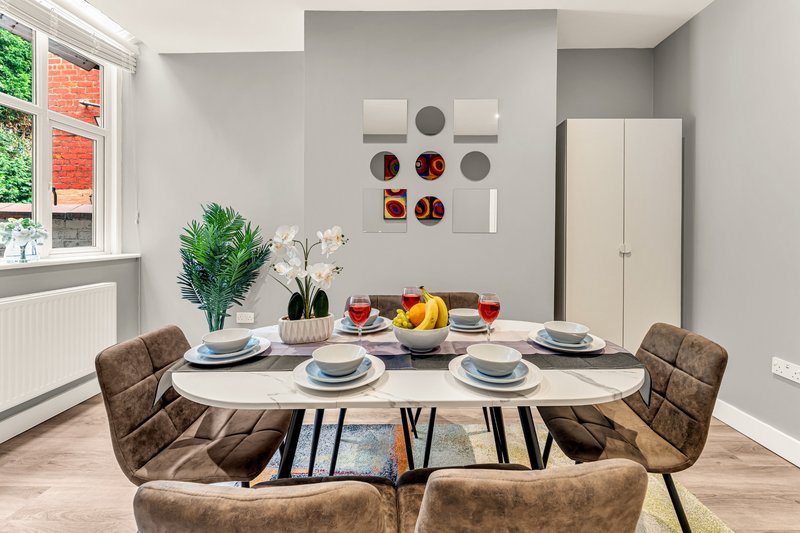 Modern dining room with oval table, brown upholstered chairs, place settings, and wall decor