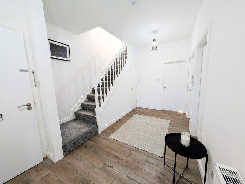 Hallway with staircase, white walls, wooden flooring and black chair