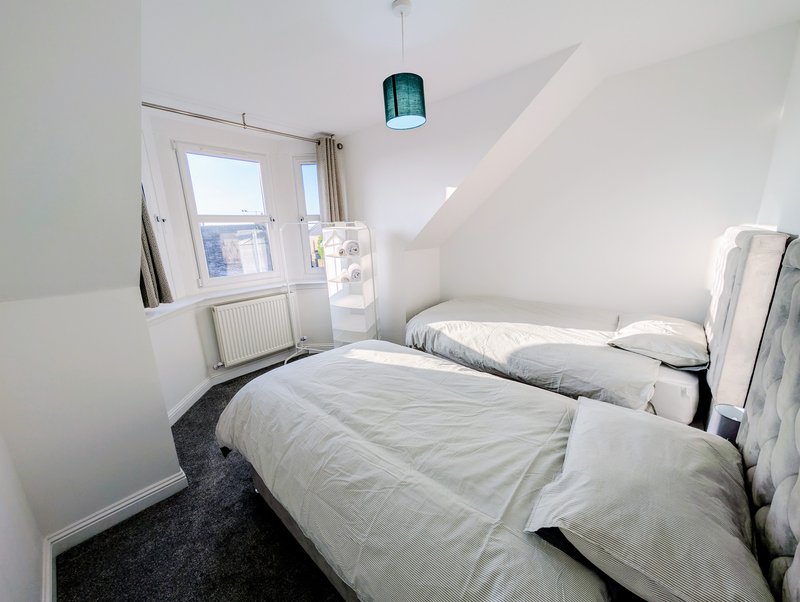 Bright attic bedroom with two single beds, skylight window, and sloped ceiling