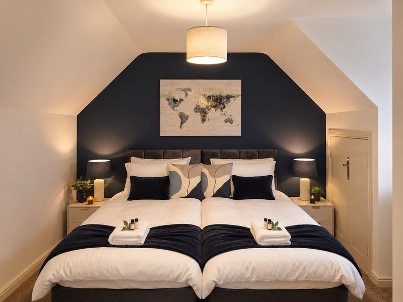 Modern bedroom with twin beds, black headboard, world map artwork, pendant light and side lamps