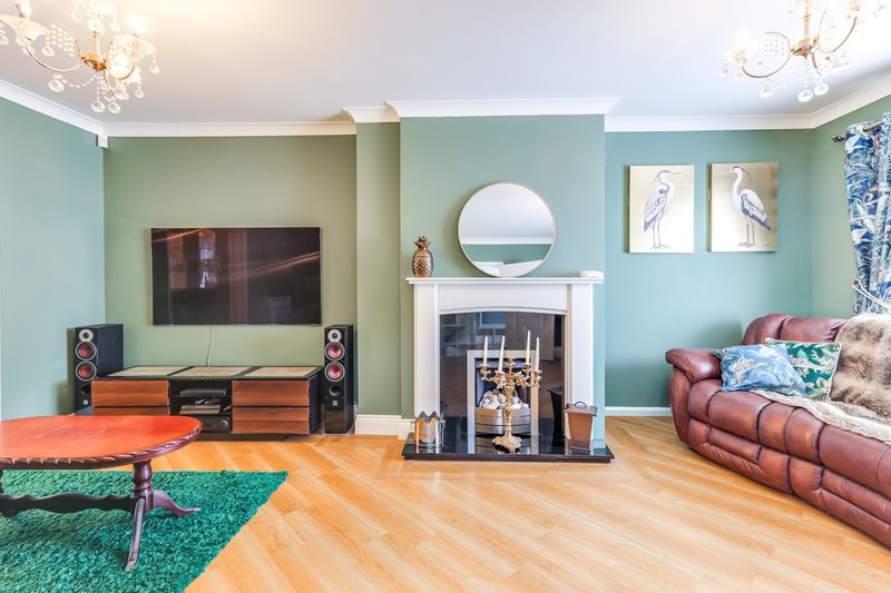 Living room with turquoise walls, fireplace, TV, burgundy sofa and wooden flooring
