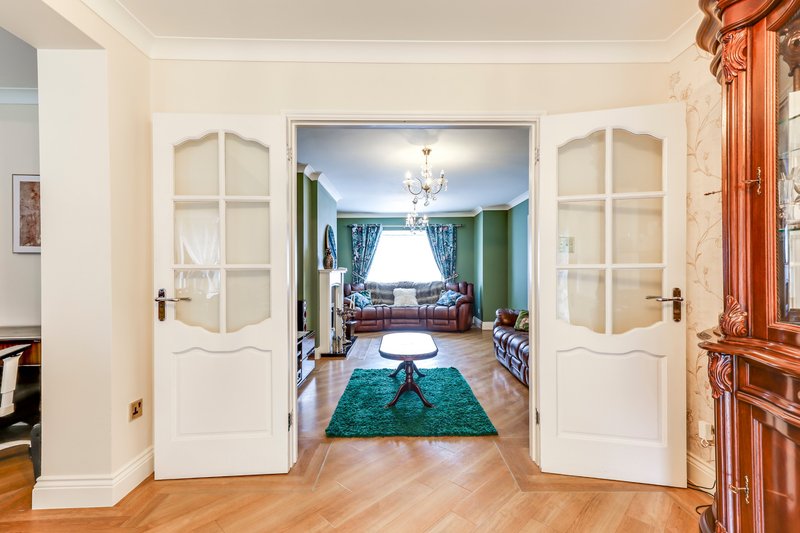 Hallway with white double doors opening to living room with turquoise rug