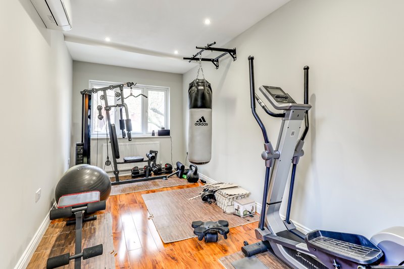 Home gym with wooden floor, exercise equipment including punching bag, stationary bike, and elliptical machine
