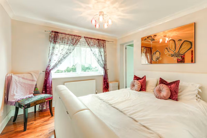 Bright bedroom with double bed, burgundy curtains, wooden floor and modern ceiling light