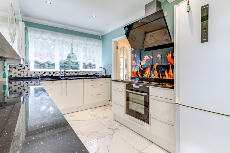 Modern kitchen with cream cabinets, marble countertops, turquoise walls and integrated appliances