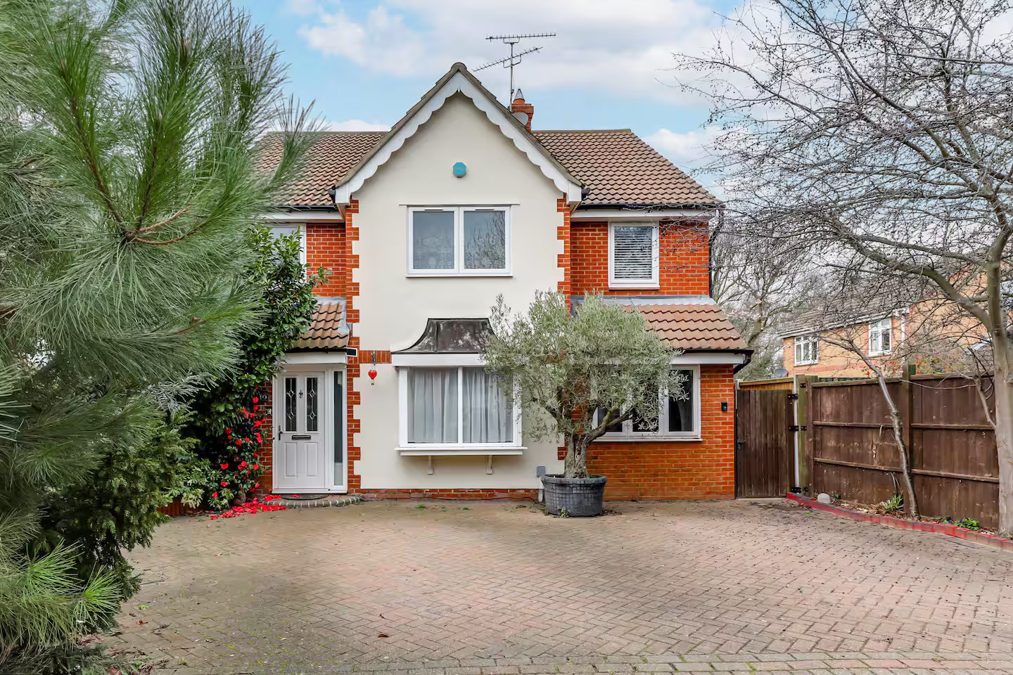 Two-storey brick and white rendered house with driveway, front garden, and brick boundary fence