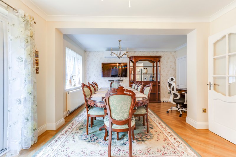 Elegant dining room with wooden table, upholstered chairs, hardwood floor and traditional furnishings