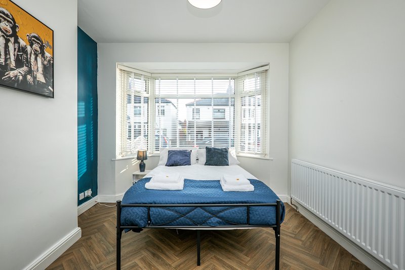 Bright bedroom with double bed, bay window, wooden floor, and city views