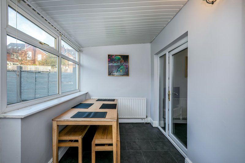 Bright sunroom with wooden dining table, chairs, radiator and glass doors to patio