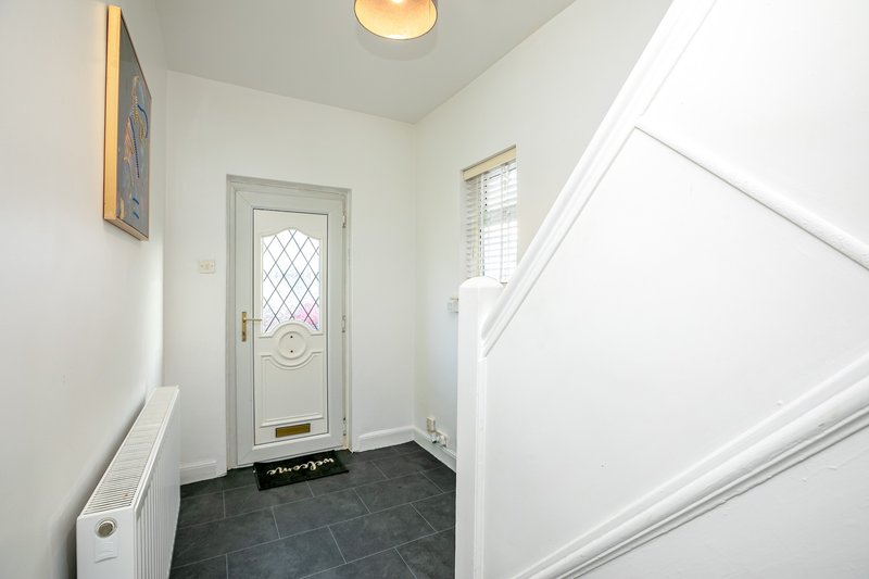 Bright entryway with gray tile floor, white walls, and staircase to the right