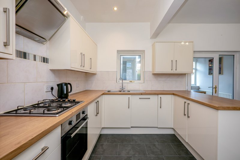 Modern kitchen with white cabinets, wooden countertops, gas range and stainless steel appliances