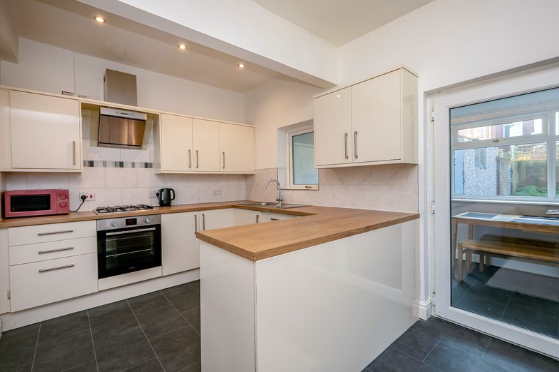 Modern kitchen with white cabinetry, wooden countertop island, and stainless steel appliances