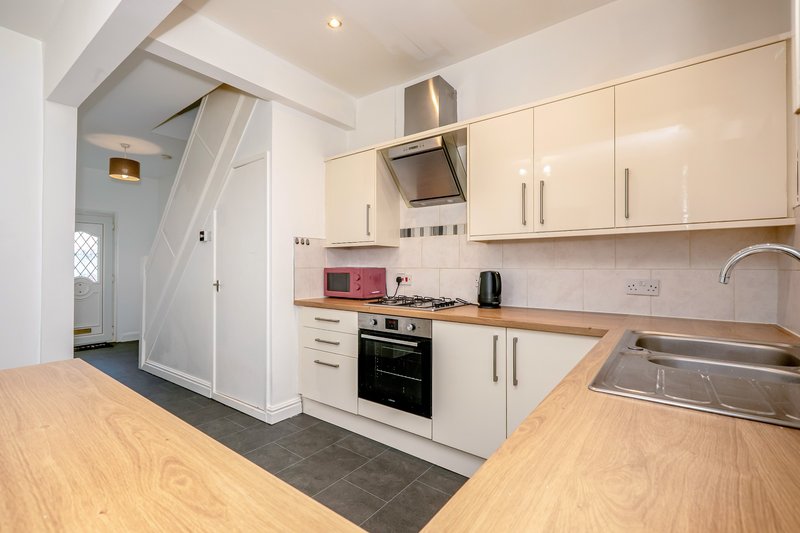 Modern kitchen with white cabinetry, wooden countertops, stainless steel appliances and wood-effect flooring