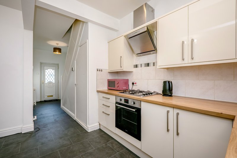 Modern kitchen with white cabinets, wood countertops, black oven and gas hob