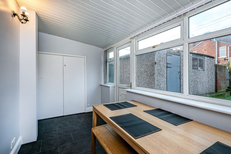 Bright entryway with wooden bench, black tile floor, white door and large windows