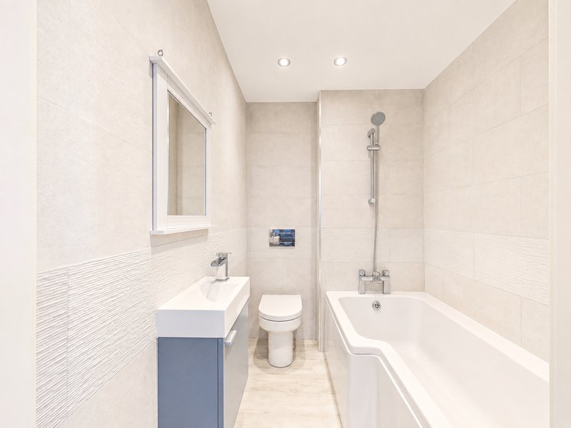 Modern bathroom with white tiles, vanity sink, toilet, bathtub and shower