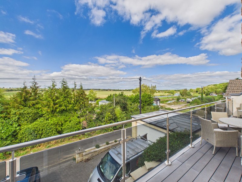 Elevated terrace with metal railings overlooking countryside, green landscape and blue sky