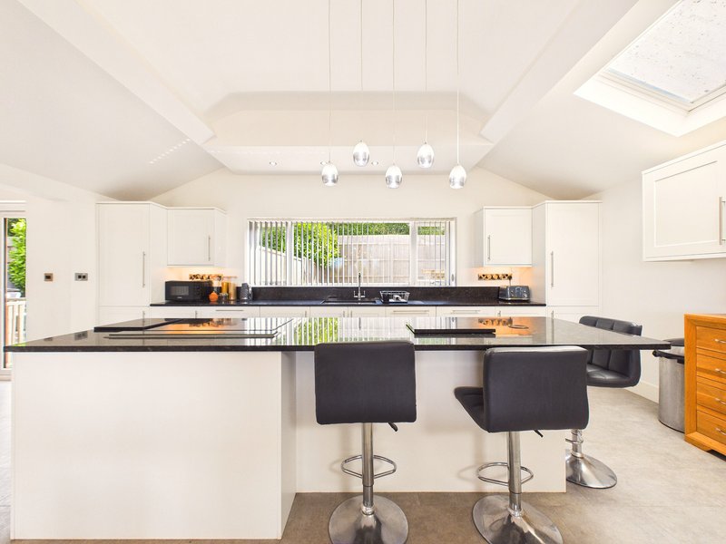 Modern kitchen with white cabinets, black countertop, island with bar seating, and pendant lighting