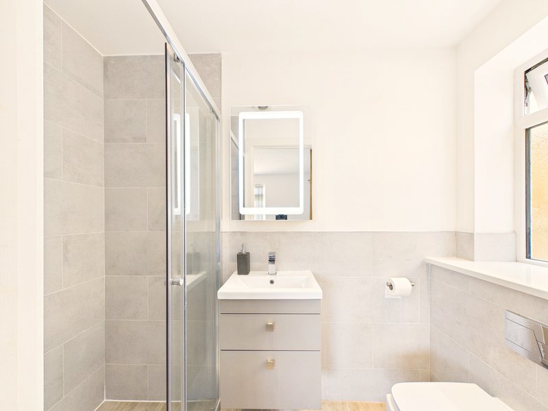 Modern bathroom with shower enclosure, white vanity, mirror and toilet