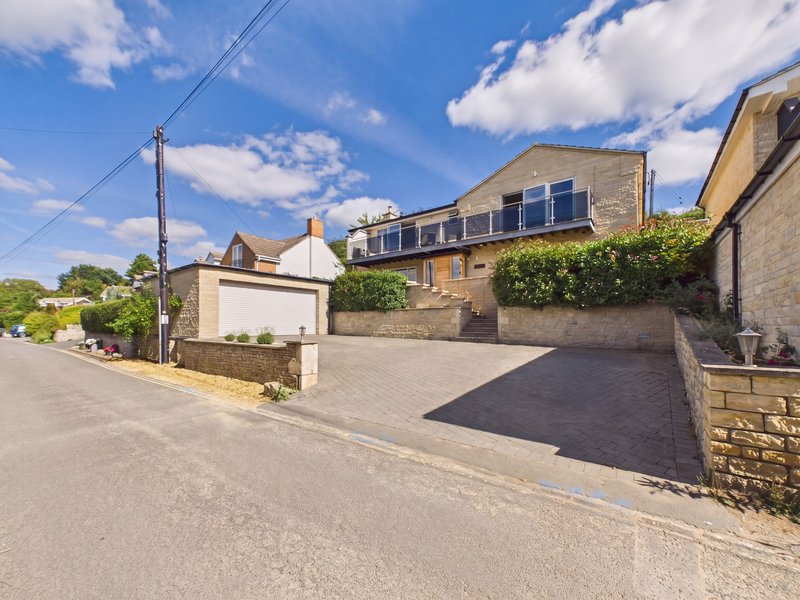 Stone and brick residential property with driveway, accessed from rural road with countryside views