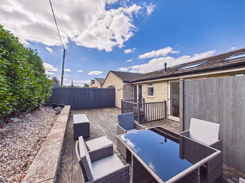 Contemporary single-storey house with paved patio, outdoor seating, and blue dining table