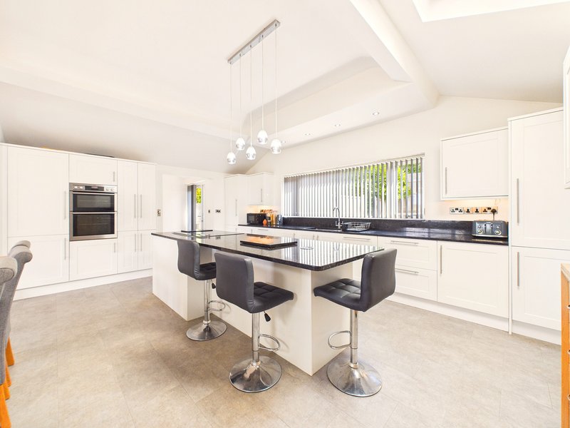 Modern open-plan kitchen with white cabinetry, central island, pendant lighting and bar seating