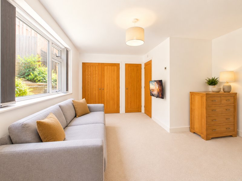 Modern living room with gray sofa, wooden doors, and natural light from large window