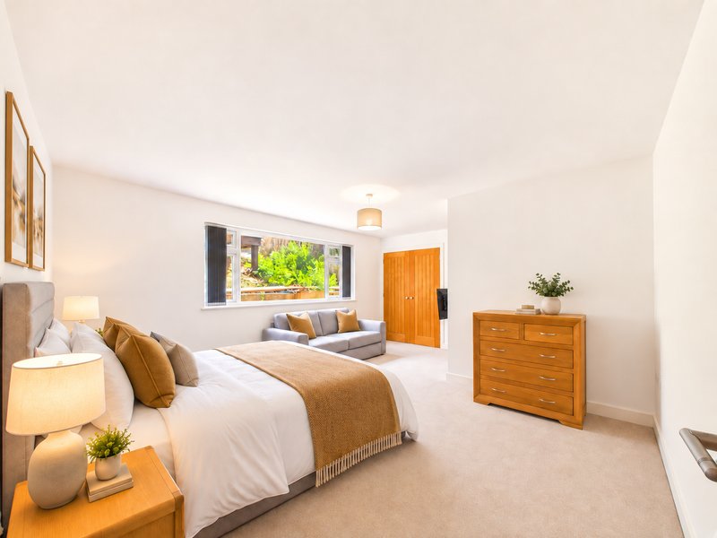 Spacious bedroom with two beds, wooden furniture, window and neutral décor