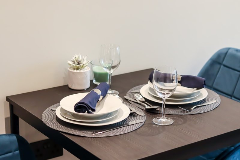 Dining table set with place settings, glasses, napkins and a small potted plant
