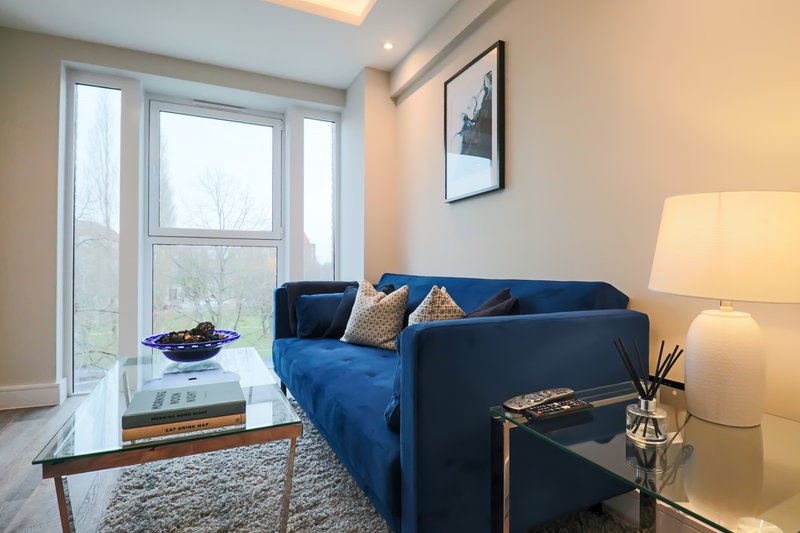 Modern living room with blue sofa, glass coffee table, floor lamp and patio doors