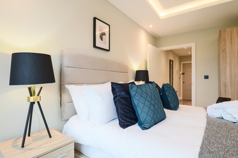 Modern bedroom with double bed, navy cushions, bedside lamp and framed wall art