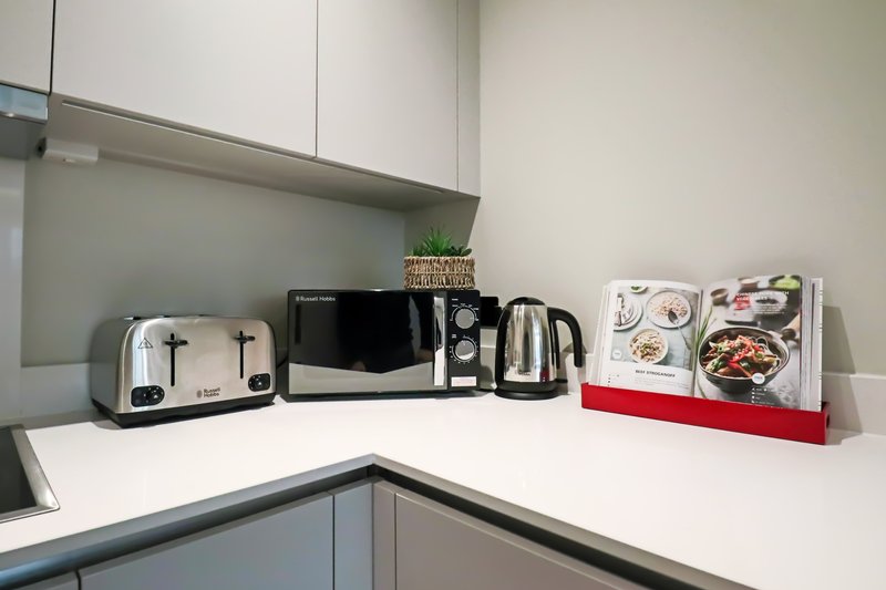 Modern kitchen counter with toaster, kettle, microwave and cookbooks in rack
