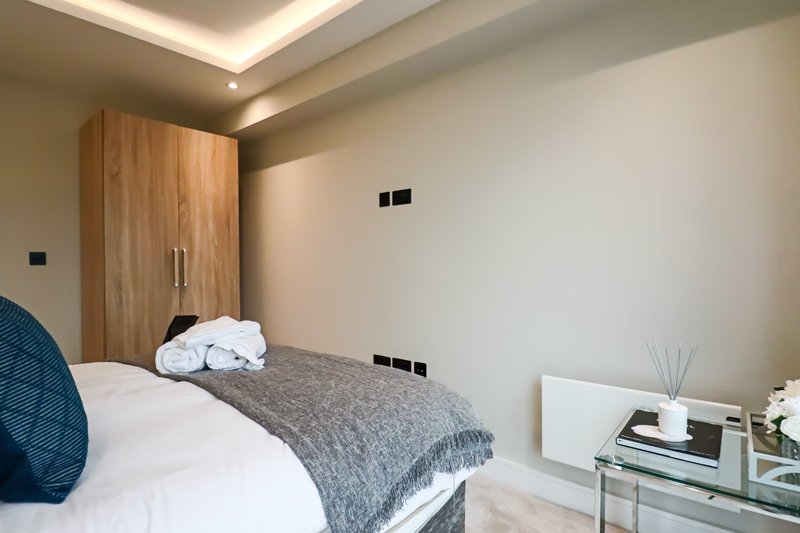 Modern bedroom with double bed, wooden wardrobe, grey bedding and contemporary ceiling lighting