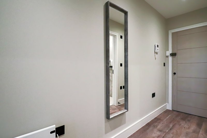 Modern hallway with tall mirror, gray doors, and wood-look flooring