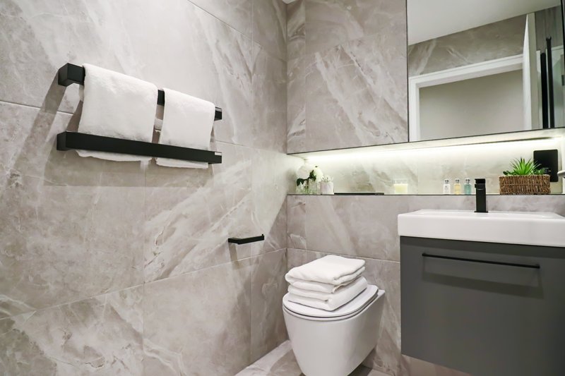 Modern bathroom with marble-effect tiles, wall-mounted towel rack, sink vanity and toilet
