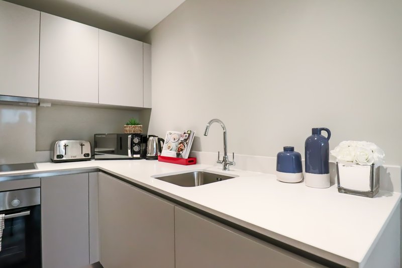 Modern white kitchen with sink, countertop appliances, and storage containers